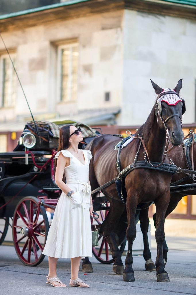 Tourist girl enjoying a stroll through Vienna and looking at the beautiful horses in the carriage